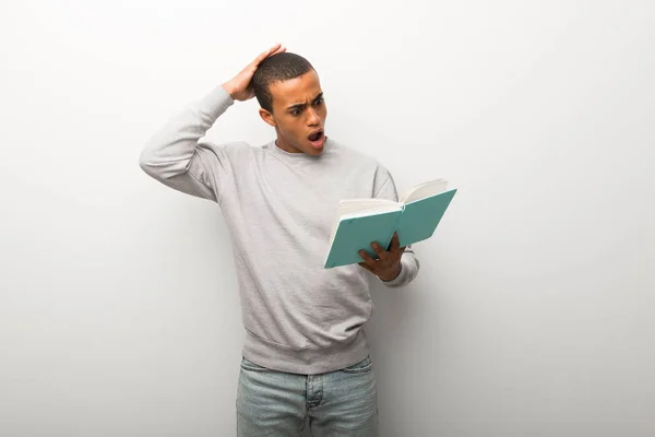 African American Man White Wall Background Holding Book Surprised While — Stock Photo, Image