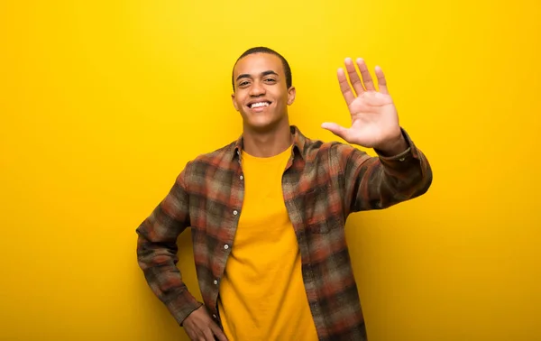 Giovane Uomo Afroamericano Vibrante Sfondo Giallo Che Saluta Con Mano — Foto Stock