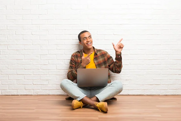 Africano Americano Sentado Chão Com Seu Laptop Apontando Com Dedo — Fotografia de Stock