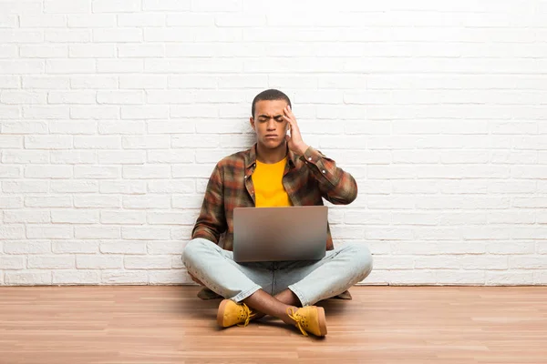 African american man sitting on the floor with his laptop unhappy and frustrated with something