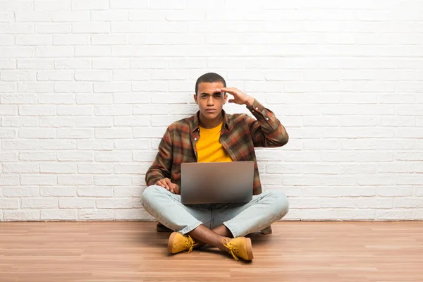 非洲裔美国人坐在地板上 他的笔记本电脑看得很远 手看东西 — 图库照片