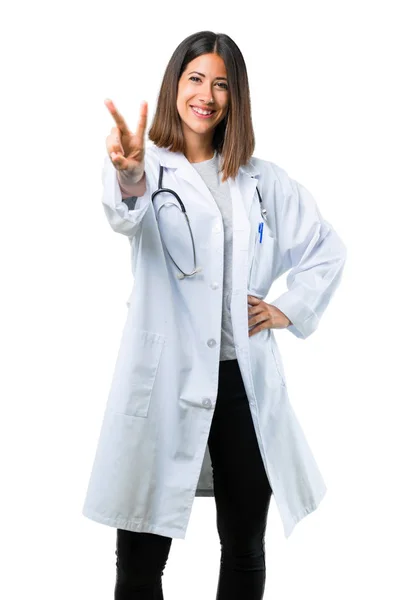 医生妇女与听诊器微笑并且显示胜利标志在被隔绝的白色背景 — 图库照片