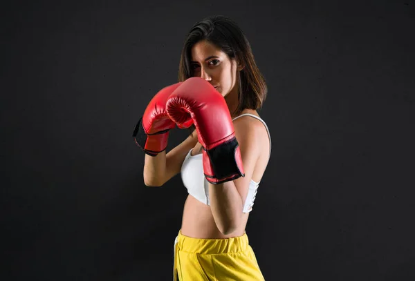 运动妇女与拳击手套在黑色背景 — 图库照片