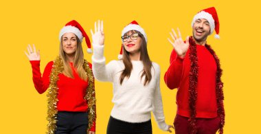 Sarı arka plan üzerinde mutlu ifade ile el ile selamlayan Noel tatili için bir grup insanlar sarışın kadın giyinmiş