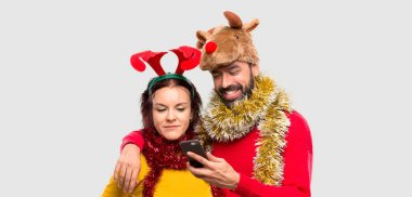 Bir mobil izole arka planda tutan Noel tatili için çift giyinmiş