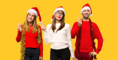 Mutlu Noel tatili için giyinmiş ve üç sarı zemin üzerine parmağınızla sayma insanlar sarışın kadın bir grup