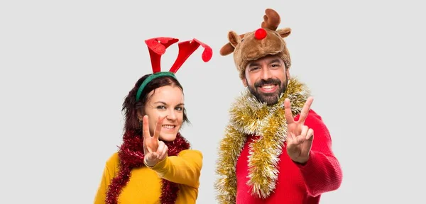 Pár Oblečená Pro Vánoční Svátky Úsměvem Ukazují Vítězství Podepsat Izolované — Stock fotografie