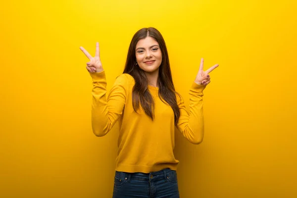 Ragazza Adolescente Vibrante Sfondo Giallo Sorridente Mostrando Segno Vittoria Con — Foto Stock