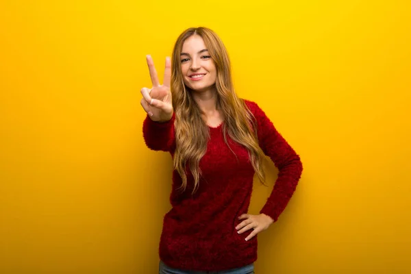 Gülümseyen Zafer Işaret Gösteren Canlı Sarı Zemin Üzerine Genç Kız — Stok fotoğraf