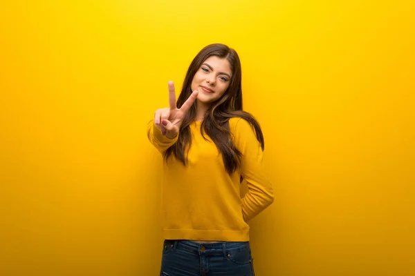 Teenager Mädchen Auf Leuchtend Gelbem Hintergrund Lächelt Und Zeigt Siegeszeichen — Stockfoto