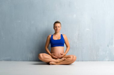 Yoga yaparken sarışın hamile kadın