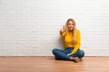 Gösteren ve en iyi iz içinde parmak kaldırma yerde oturan genç kız