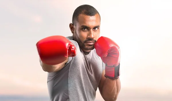 Strong sport man with boxing gloves fighting on sunset background