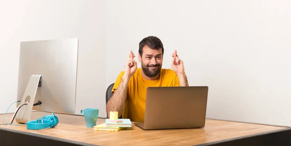 男子工作与笔记本电脑在办公室用手指交叉 并祝愿最好的 — 图库照片