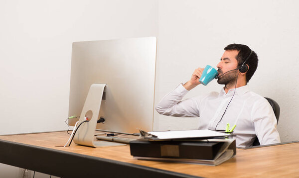 Telemarketer man in a office holding a cup of coffee