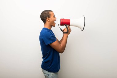 Genç Afro-Amerikan adam beyaz duvar bir megafon ile bağırarak lateral pozisyonda bir şey ilan