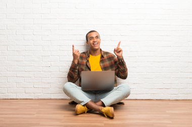 Afrika kökenli Amerikalı adam harika bir fikir işaret parmağı ile işaret onun laptop ile katta oturan