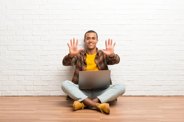 非洲裔美国人坐在地板上 他的笔记本电脑数着10手指 — 图库照片