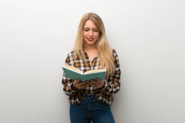 Sarışın genç kız bir kitap ve okuma zevk beyaz duvar üzerinde