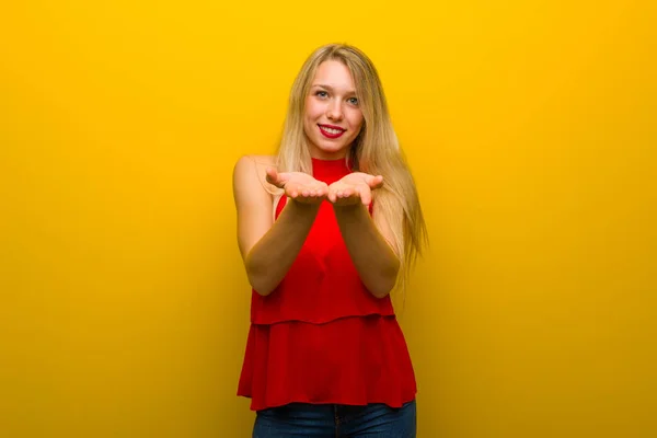 広告を挿入する手のひらに架空 Copyspace を保持している黄色の壁に赤いドレスの少女 — ストック写真