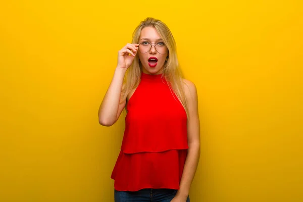 Gözlüklü Sürpriz Sarı Duvarın Üzerinden Kırmızı Elbise Ile Genç Kız — Stok fotoğraf