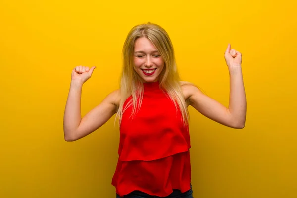 幸せとジャンプの黄色い壁に赤いドレスの少女 — ストック写真