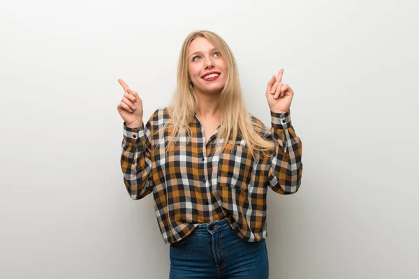 Blonde Jonge Meisje Witte Muur Wijzen Met Wijsvinger Een Geweldig — Stockfoto