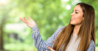 Çizgili gömlekli uzanan eller açık havada gelmek davet için yan ile genç kız