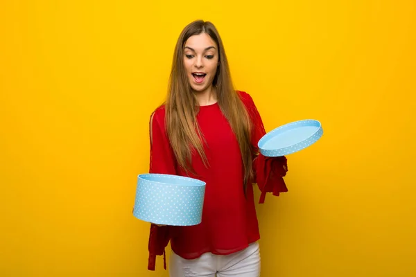 Menina Com Vestido Vermelho Sobre Parede Amarela Segurando Caixa Presente — Fotografia de Stock