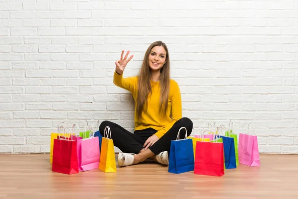Young girl with lot of shopping bags happy and counting three with fingers