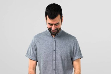 Yakışıklı adam ayakta ve gri arka plan üzerinde aşağı bakıyor