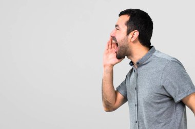 Yakışıklı adam gri arka plan üzerine açık ağızlı bağırarak