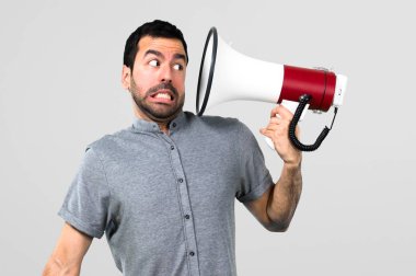 Yakışıklı adam bir megafon gri arka plan üzerinde tutan