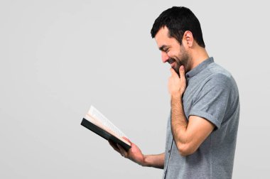 Yakışıklı adam gri arka plan üzerine bir kitap okuma