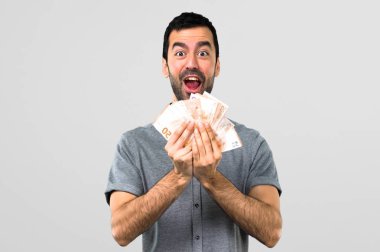 Yakışıklı adam gri arka plan üzerinde bir sürü para alarak