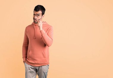 Pembe bir kazak bir büyüteç alarak ve içinden koyu sarı arka plan üzerinde seyir erkekte