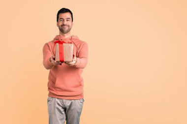 Pembe bir kazak hediye kutuları koyu sarı zemin üzerine elinde tutan adam