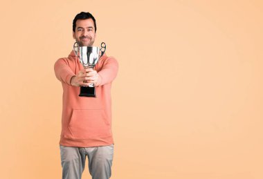 Pembe bir kazak bir kupa koyu sarı arka plan üzerinde tutan adam