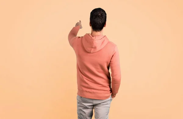 Man Pink Sweatshirt Pointing Back Index Finger Presenting Product Ocher — Stock Photo, Image