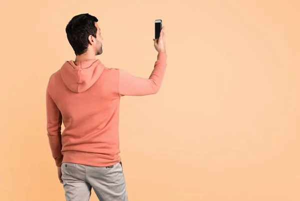 Człowiek Różowa Bluza Biorąc Selfie Mobile Tle Ochry — Zdjęcie stockowe