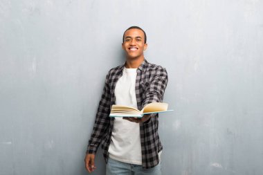 Bir kitap ve birine vererek kareli gömlek ile genç Afro-Amerikan adam