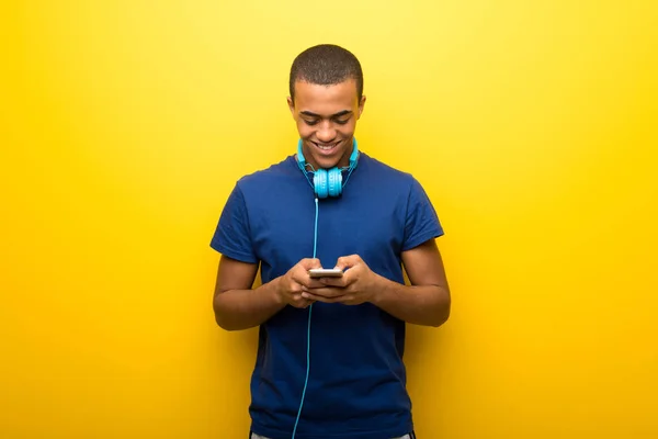 Hombre Afroamericano Con Camiseta Azul Sobre Fondo Amarillo Enviando Mensaje —  Fotos de Stock