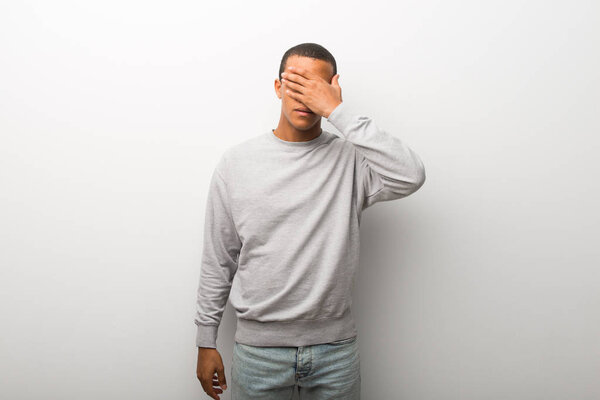 African american man on white wall background covering eyes by hands. Do not want to see something