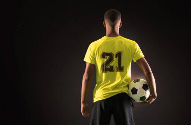 Elleri ile bir topu yakalıyor koyu arka plan üzerinde oynarken futbol oyuncu adam ile koyu derili