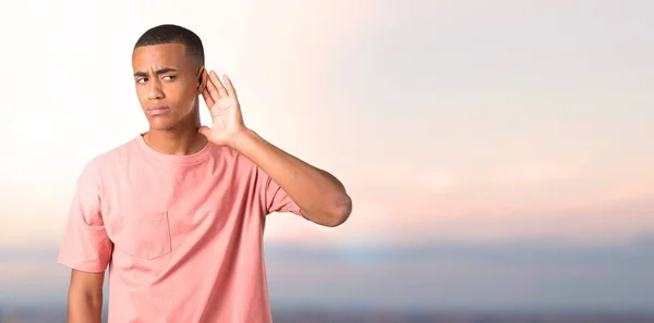 Homem Pele Escura Ouvindo Algo Colocando Mão Orelha Fundo Pôr — Fotografia de Stock