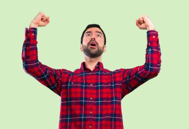 Yakışıklı adam yeşil arka plan üzerinde bir zafer kutluyor