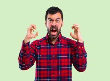 Yakışıklı adam kızgın yeşil zemin üzerine öfkeli jest olarak rahatsız