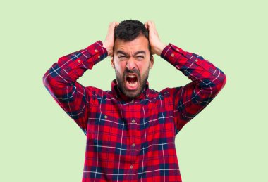 Yakışıklı adam kızgın yeşil zemin üzerine öfkeli jest olarak rahatsız