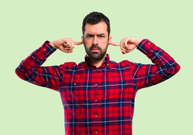 Yakışıklı adam her iki kulak elle yeşil zemin üzerine kaplama