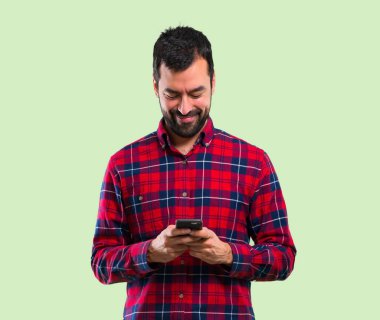 Yakışıklı adam cep telefonuyla yeşil arka plan üzerinde